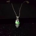 Detailed view of skull pendant with glowing green eyes and nose on silver chain - Green