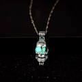 Close-up of silver skull pendant with luminous green glowing eyes on a dark background - Light Blue Glow