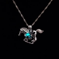 Dettaglio di un ciondolo a forma di cavallo traforato con perla blu luminosa su nero - Bagliore Blu Chiaro