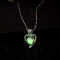 Macro d'un collier pendentif coeur lumineux brillant en vert sur un fond sombre - Vert