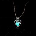 Détail macro d'un pendentif cœur évidé avec pierre lumineuse bleue sur chaîne argentée - Lueur Bleu Clair