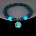 Detailed macro view of glowing turquoise yoga beads and luminous Buddha head metal pendant - Blue Turquoise Silver Finish Blue Glow