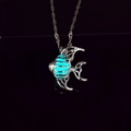 Dettaglio macro di una collana con ciondolo a forma di pesce luminoso e nucleo blu - Bagliore Ciano