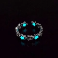 Close-up of luminous star ring glowing in dark with blue fluorescent hollow design - Silver Teal Glow