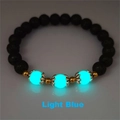 Macro detail of elastic bracelet with black lava stone beads and light blue luminous accents - Cyan Glow