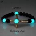 Vista macro della perla luminosa blu e della croce in strass dorati sul bracciale con perline - Oro Antico Luce Blu Chiaro