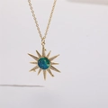 Dettaglio del ciondolo a sole dorato con smalto blu-verde e accenti in zircone lucido - Stile Sole a Raggiera (XL2052)
