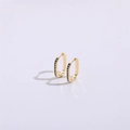 Detalle de los pendientes en forma de U dorados con piedras de circón negro en fondo lila - U-Shaped Zirconia Ear Buckle