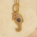 Seahorse pendant necklace in 14K gold plating with white zircons and blue evil eye detail - Seahorse