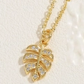 Detailed close-up of a 14K gold plated monstera leaf pendant with sparkling zircons - Monstera Leaf / 14K Gold