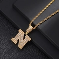 Detailed macro view of gold letter N pendant with white zircon on black leather - Letter N / Rope Chain Necklace / Gold