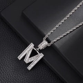 Macro detail of iced-out silver letter M pendant with zircon stones and rope chain - Letter M