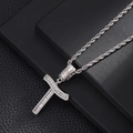 Macro shot of iced out silver cross pendant with baguette-cut zircons and rope chain - Cross