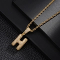 Close-up of gold twist chain necklace with H-letter pendant paved in sparkling zircons - Letter H Style