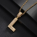Detail of gold L-shaped pendant with cubic zirconia inlay on a black leather surface - Letter L Style