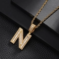 Detailed close-up of golden letter N pendant with cubic zirconia on black leather - Letter N Style