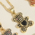 Macro view of gold teddy bear pendant necklaces with micro-paved black heart zircons - Black Heart Bear