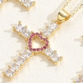 Makroaufnahme Goldkreuz-Anhänger mit klaren Kristallen und rosa Herz-Detail - Rosenrotes Herz