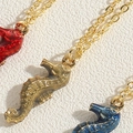 Macro view of colorful enamel seahorse pendants with golden chains in three distinct colors - Gray