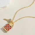 Vue macro du pendentif serrure et clé en or avec émail rouge à damier et zircons - Émail Rouge