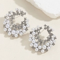 Macro shot of silver C-shaped earrings with faux pearls and crystals on white stones - Round Pearl Rhinestone Earrings
