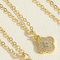 Macro shot of gold clover pendant necklace with sparkling cubic zirconia on textured paper - Four Leaf Clover Zirconia Necklace (MA1-8) / Gold