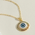 Close-up of golden evil eye pendant necklace with rainbow zircon stones and blue pupil - Rainbow Zirconia Circle Design