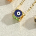 Vue macro du pendentif cube doré avec motifs œil maléfique colorés et finition polie - Coloré