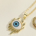 Macro shot of evil eye pendant with blue zircon and golden eyelashes on a fine link chain - Double Eyelash Vivid Style