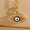 Detalle macro del collar con colgante de ojo turco dorado, cristales y esmalte negro - Negro