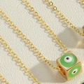 Golden necklace with cube pendant featuring green enamel evil eye dice design details - Green