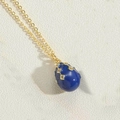 Macro shot of a dark blue enamel egg pendant with gold trim and crystal stones - Sapphire Blue