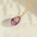 Gold chain necklace featuring a purple enamel egg pendant with a sparkling zircon flower - Purple