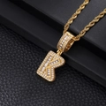 Macro shot of iced-out gold letter K pendant with sparkling cubic zirconia on rope chain - Letter K / Gold