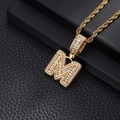 Macro detail of gold-plated M letter pendant with shimmering cubic zirconia and rope chain - Letter M / Gold
