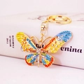 Close-up of colorful crystal butterfly keychain with gold spring clasp on a white book - Lake Blue Colorful