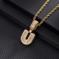 Macro detail of iced-out gold U-letter pendant with pavé zircons on black leather - Letter U / Gold