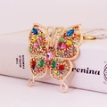Goldener Schmetterling-Schlüsselanhänger mit bunten Strasssteinen und weißen Perlendetails - Bunt