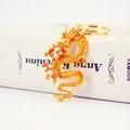 Gouden draak sleutelhanger met emaille afwerking op boekachtergrond, elegant accessoire - Goud