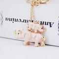 Pink enamel rhino keychain with sparkling rhinestones and golden accents on white book - Champagne