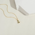 Collana con ancora placcata in oro con ciondolo in zircone verde su sfondo bianco - Stile Ancora / Oro