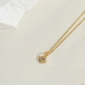 Detail shot of a golden Saturn pendant with colorful zircon stones on a white rock background - Planet Pattern Style / Gold