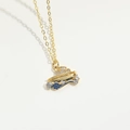 Detail of a golden necklace featuring a sailboat pendant with blue and white zircons - Ship