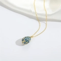 Detailed close-up of retro blue enamel egg pendant with gold floral relief and rhinestones - Sapphire Blue