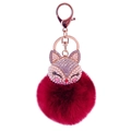 Macro shot of a fox head keychain with red faux fur ball and rose gold crystal details - White Fox Head + Dark Red Fur Ball