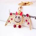 Golden bat keychain with white rhinestones and magenta gems on a white box - Fuschia