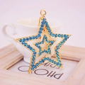 Porte-clés étoile évidée dorée avec strass bleus exposé sur une tasse blanche - Bleu