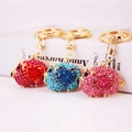 Sparkling rhinestone pig keychain with gold metal clasp on a white book background - Random Color