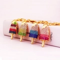 Colorful rhinestone ice cream keychains in gold finish hanging on a white book edge - Random Color