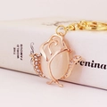 Portachiavi rosa dorata con opale e strass brillanti su una superficie di libro bianco - Imballaggio Individuale / Oro/Bianco Latte